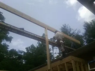 Carpenter setting a ridge beam over a new addition frame — Ice Dam Removal by Roofing Brothers in Kyles Ford