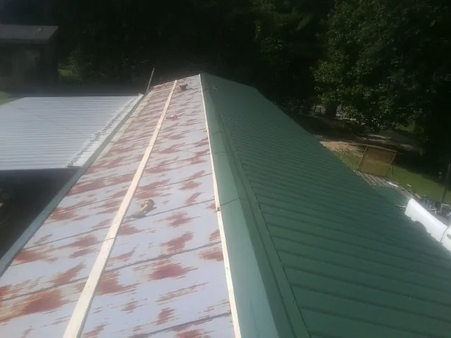Old rusted panels beside newly installed green metal roofing — Wind Damage Roof Repair by Roofing Brothers in Kyles Ford