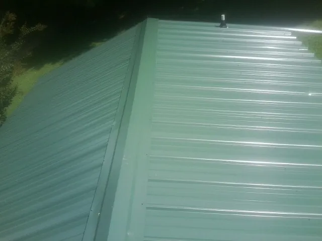 New green metal panels meeting at the ridge of a roof — Flat Roof Repair work by our crew in Kyles Ford