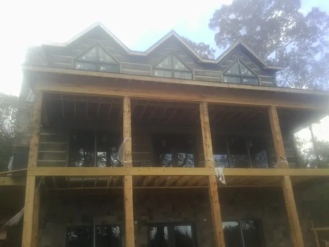 Dormers and porch framing on a large log home under construction — Roof Coating work by our crew in Kyles Ford
